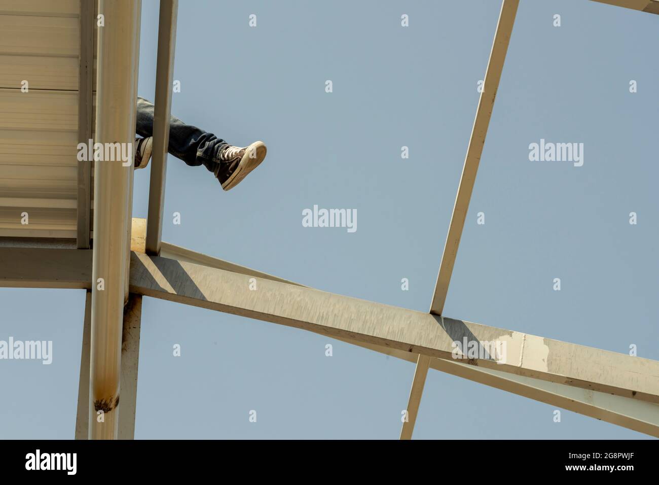 L'addetto alla costruzione si stese sulla lamiera del tetto su truss di acciaio leggero e costruzione del telaio. Foto Stock