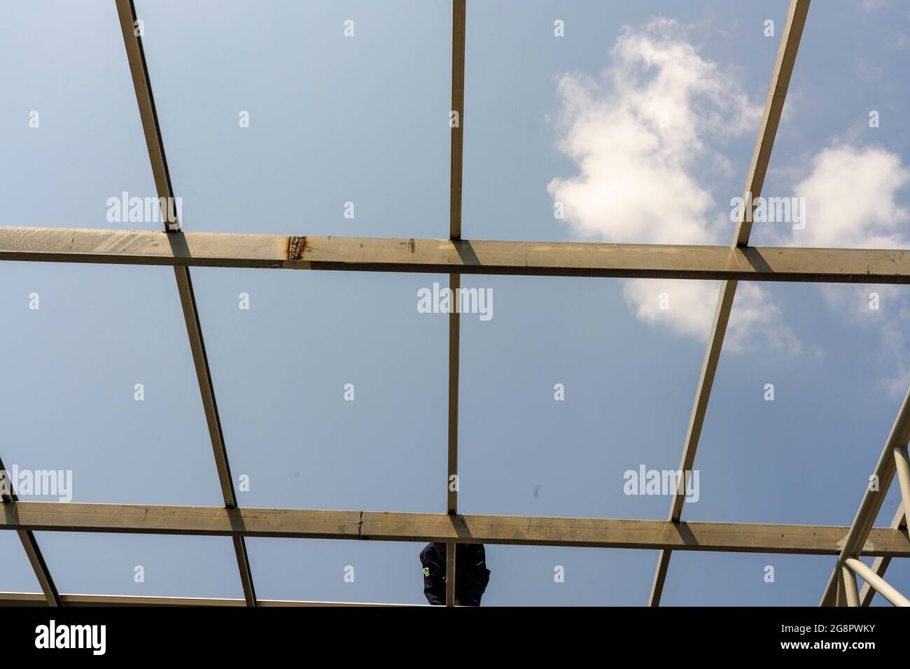 I lavoratori edili stanno installando la lamiera per tetti su truss in acciaio leggero e costruzione di telai. Foto Stock