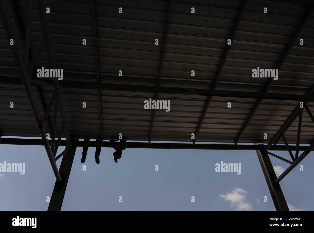 Due uomini stanno rilassando la lamiera del tetto su truss di acciaio leggero e costruzione di telaio. Foto Stock