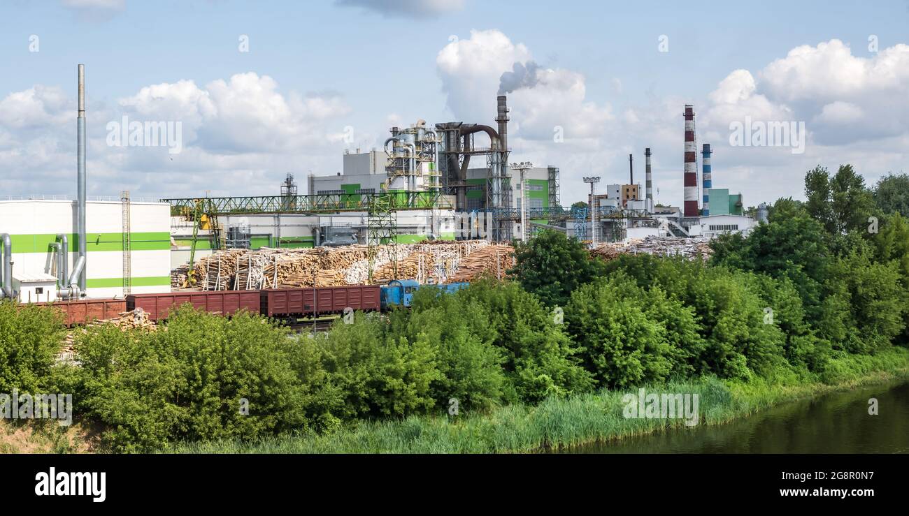 tubi di legno impresa segheria pianta vicino fiume. Concetto di inquinamento dell'aria. Paesaggio industriale inquinamento ambientale spreco di energia termica p Foto Stock