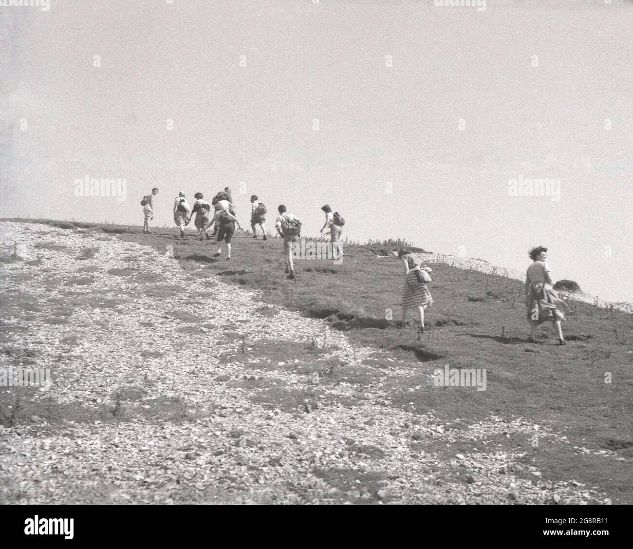 Anni '50, storico, un gruppo di rambler adulti, alcuni con scricci di tela, altri con scacchi a mano, fuori a piedi sul promontorio chalky a Beachy Head, vicino Eastbourne, East Sussex, Inghilterra, Regno Unito. Beachy Head è la più alta scogliera di mare di gesso in Gran Bretagna ed è un luogo famoso per le passeggiate di piacere, con magnifiche viste sul canale Inglese. Foto Stock