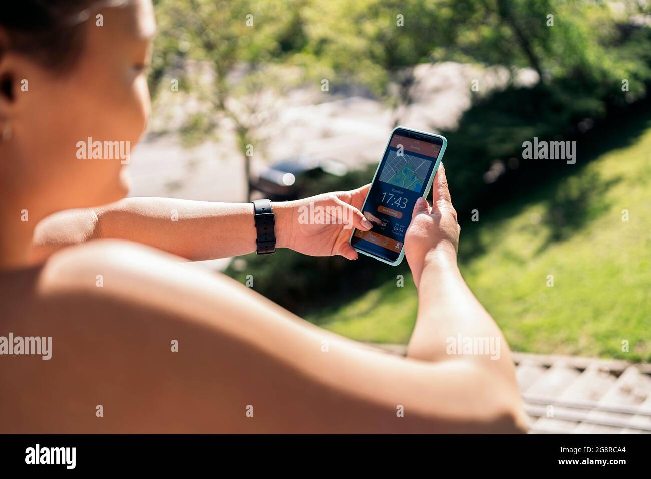 Donna attiva non riconosciuta con abiti sportivi utilizzando il suo telefono cellulare e controllare il suo allenamento. Foto Stock