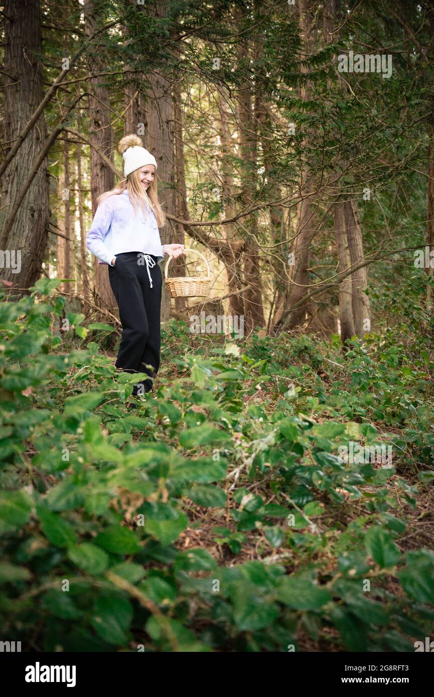 Young Girl che cammina attraverso i boschi tenendo in mano il cestino pasquale Foto Stock