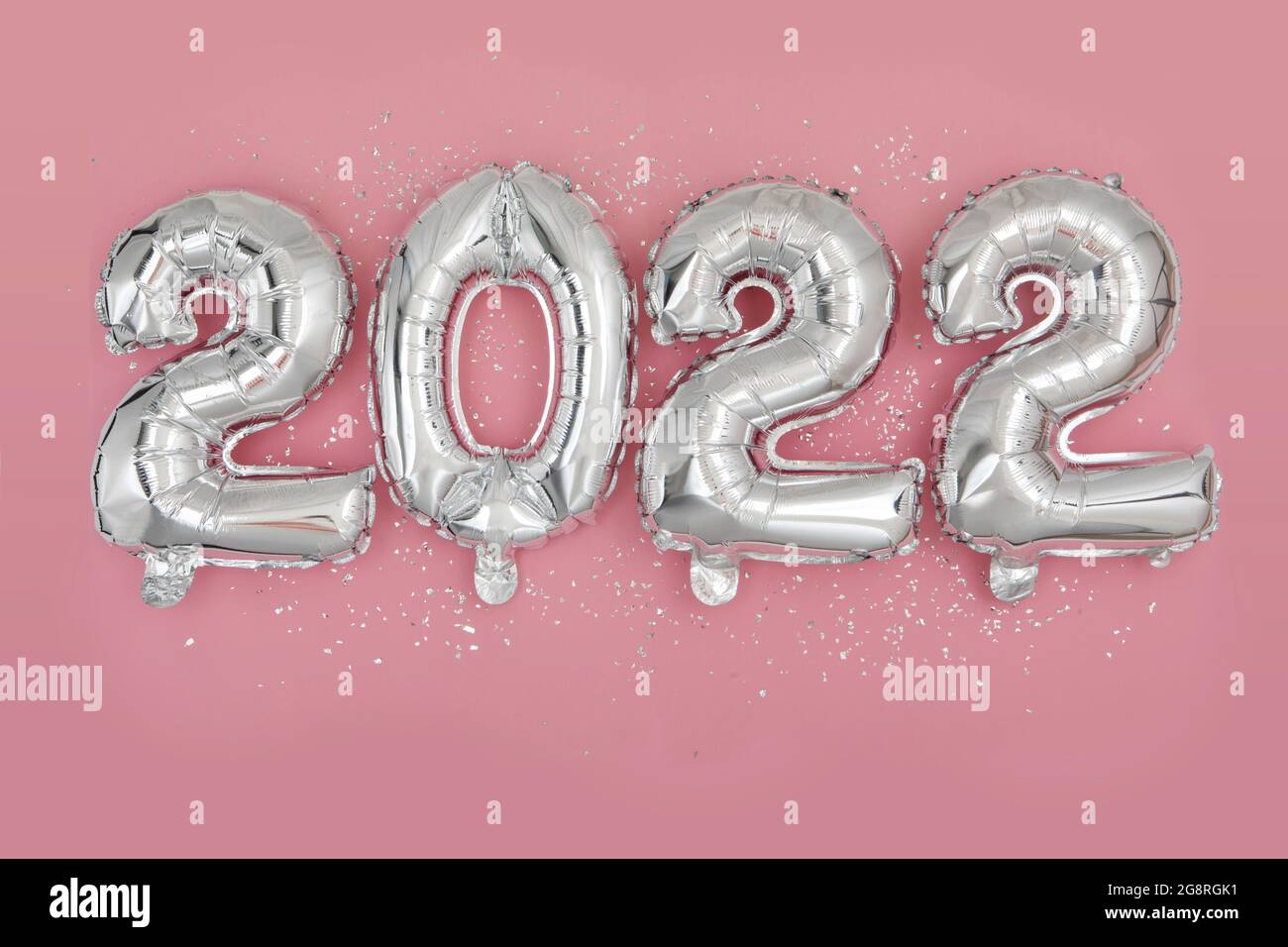 Palloncini d'argento con lamina numero 2022 e confetti su sfondo rosa Felice anno nuovo 2022 celebrazione Flat Lay Foto Stock