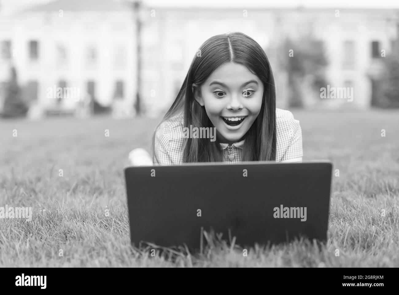 sorpresa adolescente ragazza rilassarsi nel parco su erba verde presso il cortile della scuola, computer dipendenza concetto Foto Stock