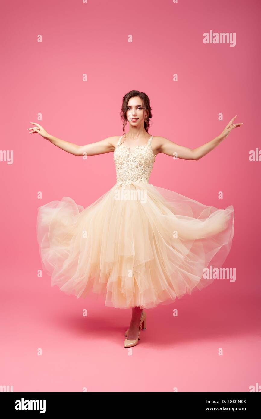 Una giovane donna sta ballando in una lunga abito beige senza maniche. Una  brunetta in un abito lussureggiante con un corset decorato e scarpe beige  sta girando sopra Foto stock - Alamy