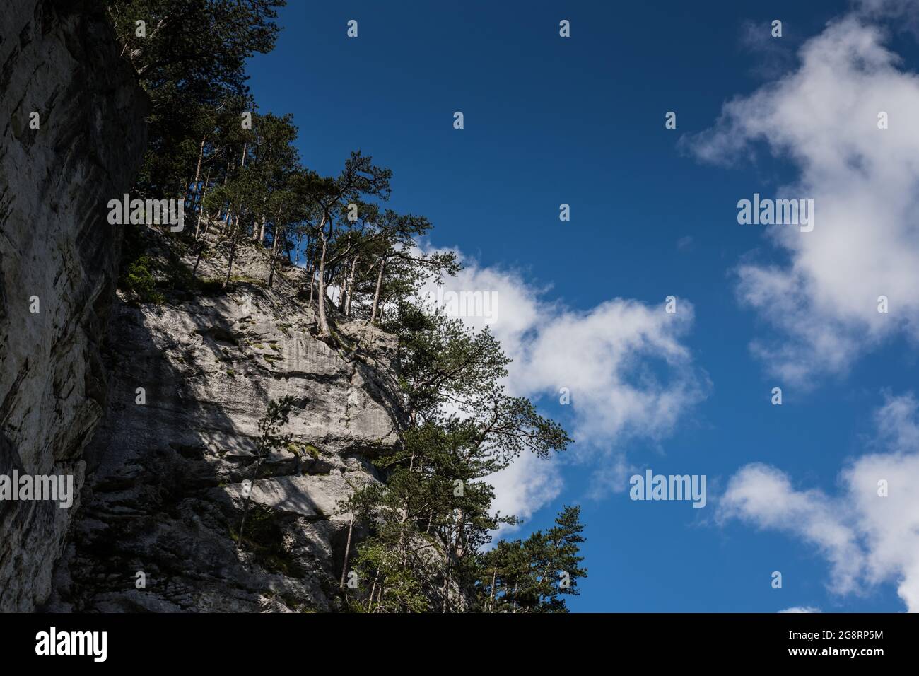 alto rockface con alberi e bellissimo cielo blu con le nuvole Foto Stock