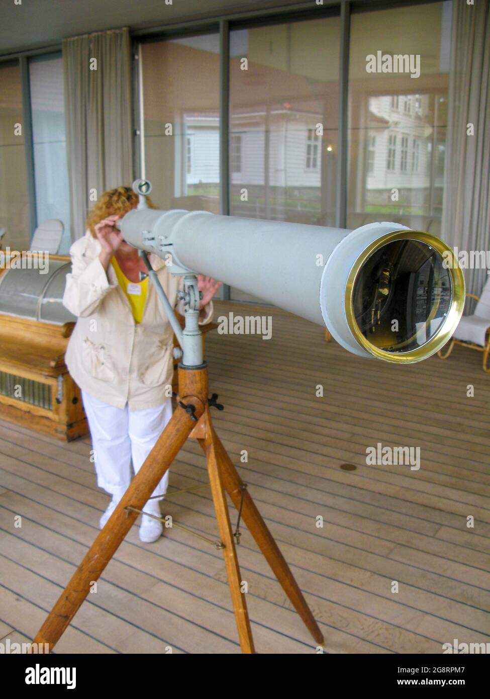 Una donna sta guardando qualcosa in lontananza attraverso una grande nave vecchio Spyglass. Indagini giornalistiche con mezzi improvvisati. Foto Stock