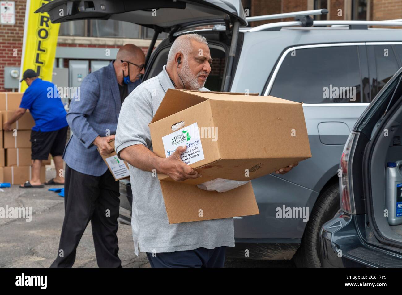 Detroit, Michigan, Stati Uniti. 22 luglio 2021. I membri del Michigan Muslim Community Council scaricano pacchetti di agnello da distribuire ai poveri durante la vacanza Eid al-Adha. EID al-Adha commemora la storia, comune a musulmani e cristiani, in cui Dio chiese a Ibrahim (Abramo) di sacrificare il figlio, ma all'ultimo minuto sostituì invece un agnello. Durante le vacanze musulmani macellaio un agnello, tenendo parte della carne e donando il resto a chiunque in bisogno. Credit: Jim West/Alamy Live News Foto Stock