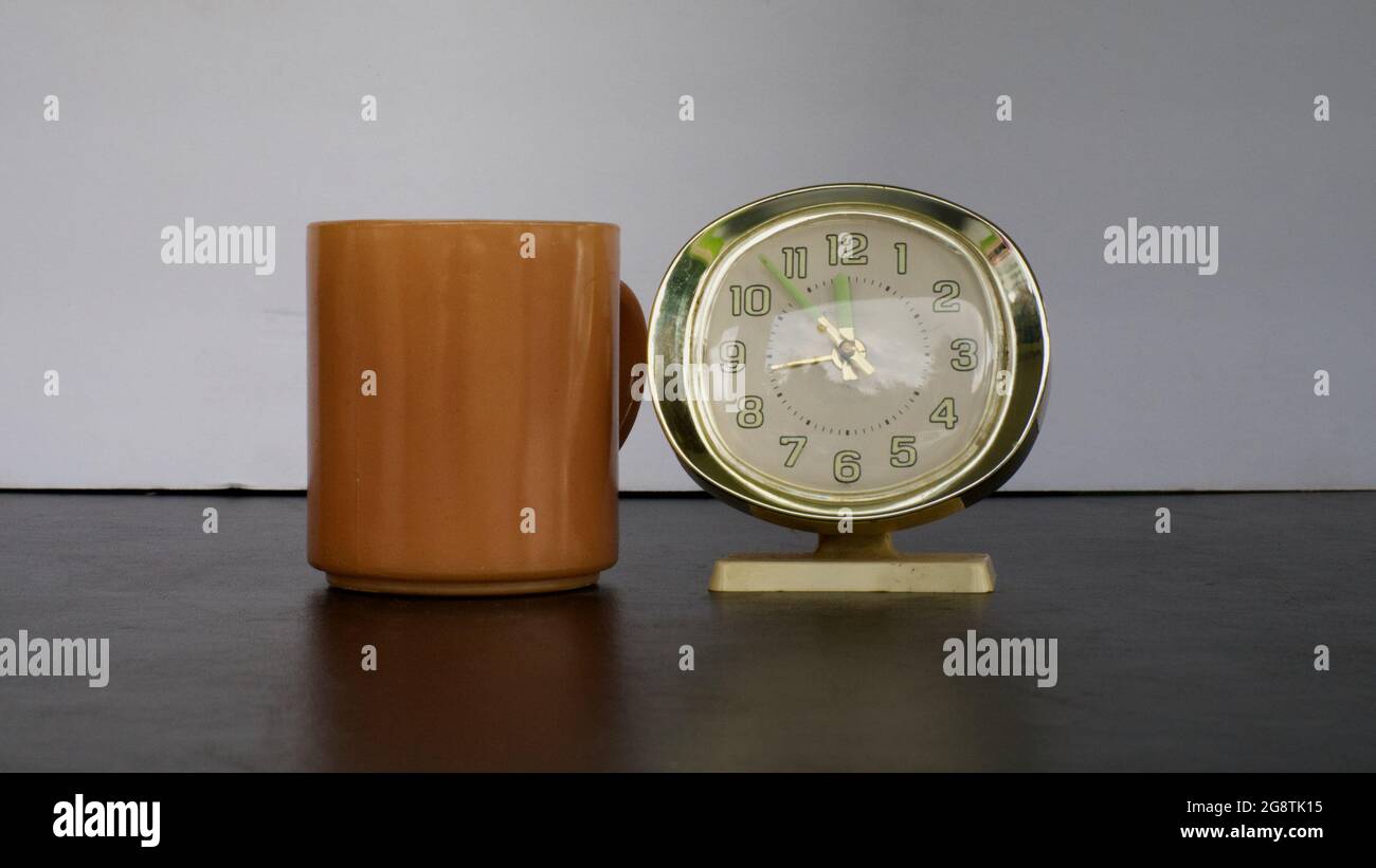 Una tazza di caffè marrone e una sveglia di vecchio stile Foto Stock Una tazza di caffè marrone e una sveglia di vecchio stile Foto Stock