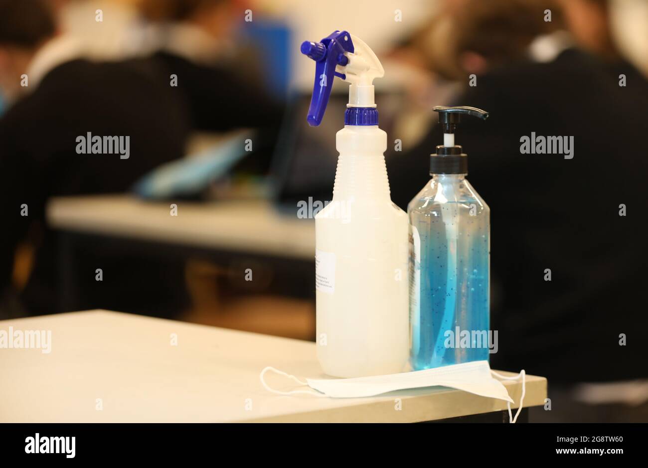 Maschera facciale, disinfettante e igienizzante per le mani su una scrivania all'interno di una scuola. Concetto di ambiente scolastico sicuro Covid e di pratiche di lavoro sicure. Foto Stock