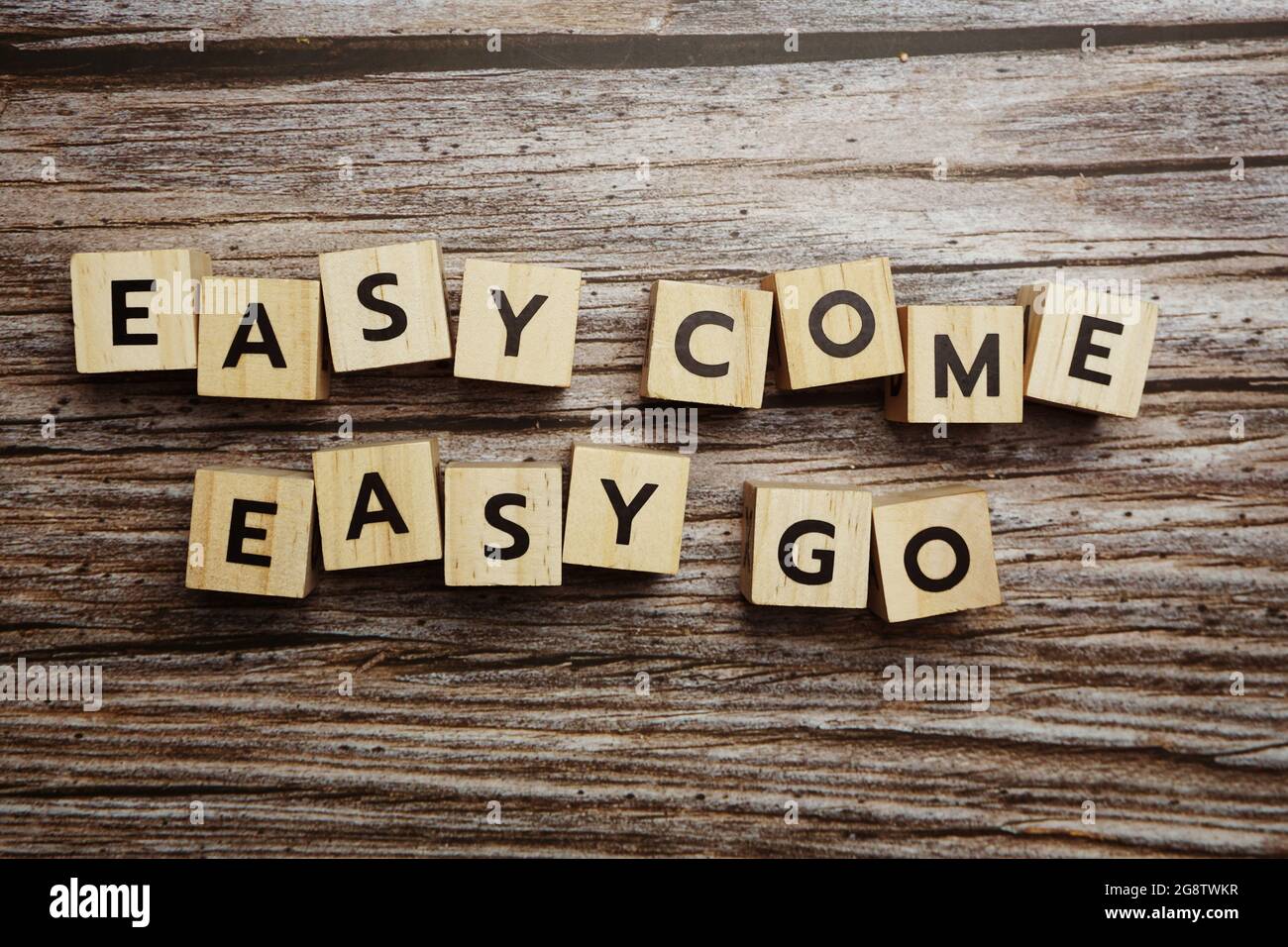 Lettere alfabetiche Easy come Easy Go su sfondo di legno; Foto Stock