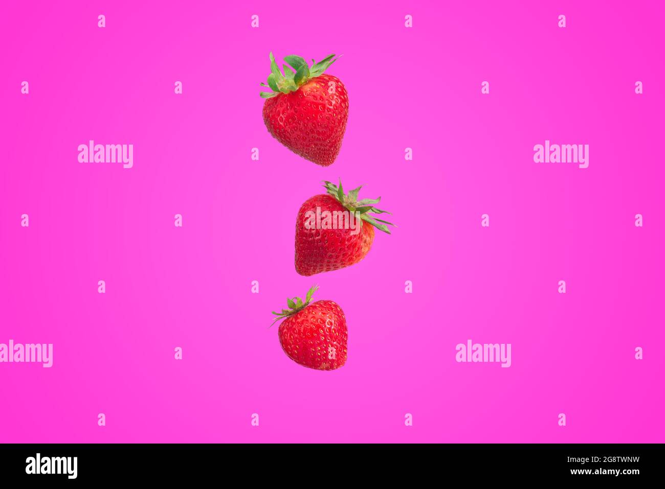tre fragole fresche che volano su sfondo rosa, stile minimalista, carta da parati, frutta Foto Stock