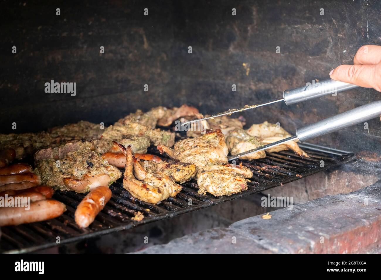Barbecue tradizionale (BBQ) su una griglia di mattoni e carbone, con una varietà di carni Foto Stock