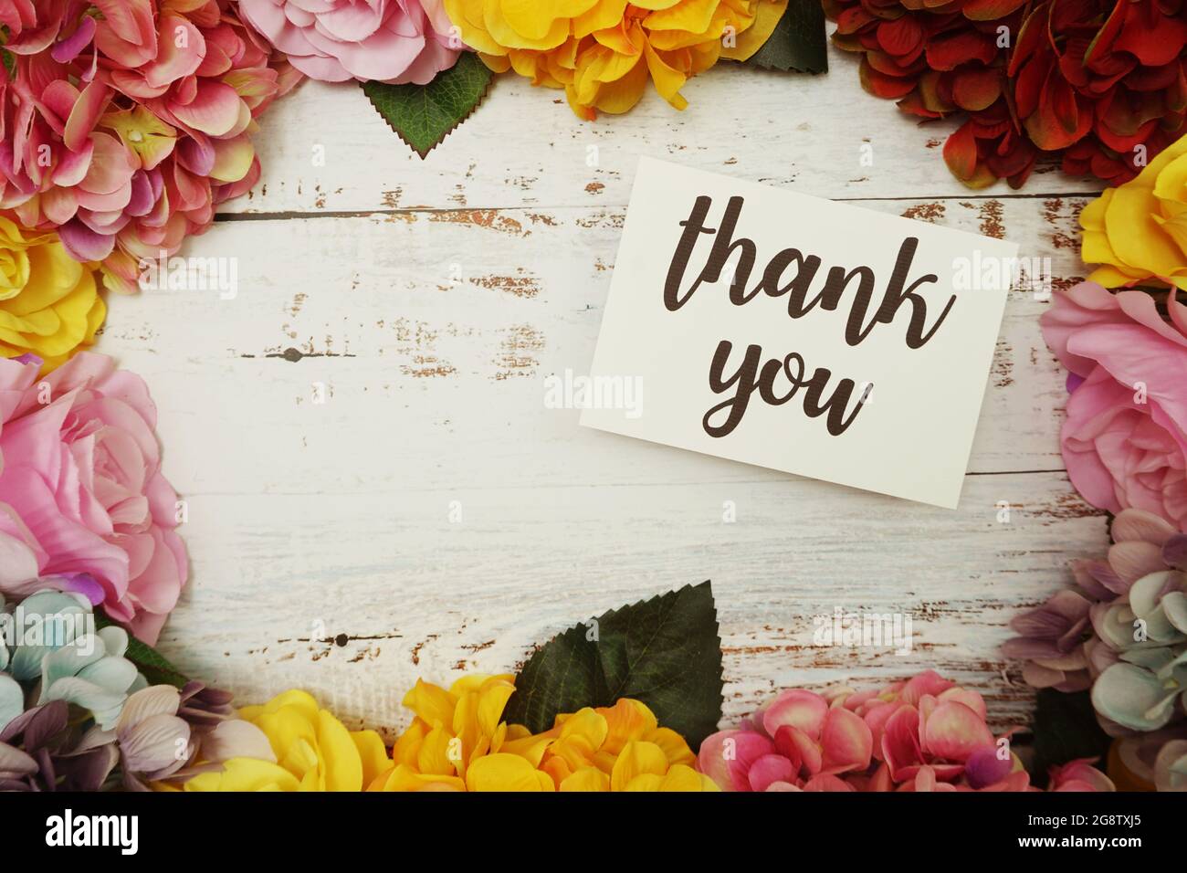 Cartolina di ringraziamento con bordo di fiori colorati su sfondo di legno Foto Stock