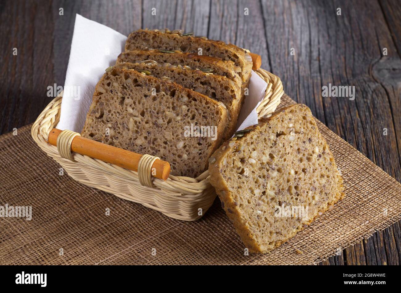 Fette di pane con semi diversi in cestello su tavolo di legno scuro Foto Stock