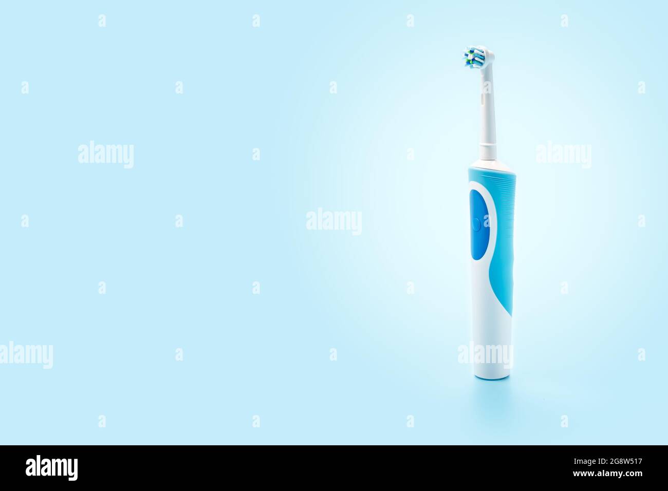 Lo spazzolino elettrico è verticale su sfondo blu. Strumenti di cura dentale su sfondo bianco. Concetto di buona igiene della bocca. Spazzolino elettrico, clos Foto Stock