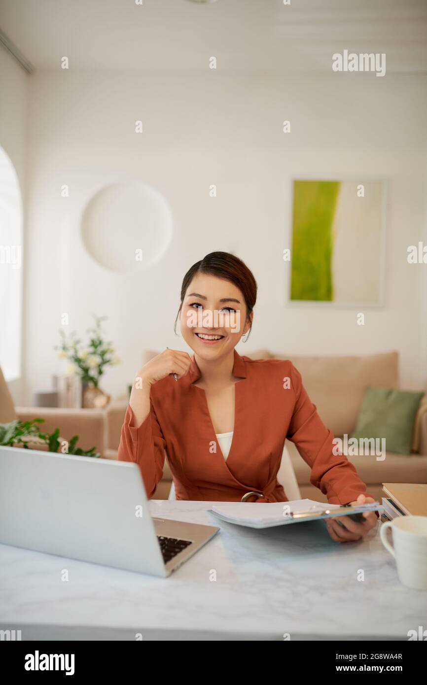 Adorabile, intelligente, giovane donna sorridente che lavora seduto in ufficio presso la postazione di lavoro Foto Stock