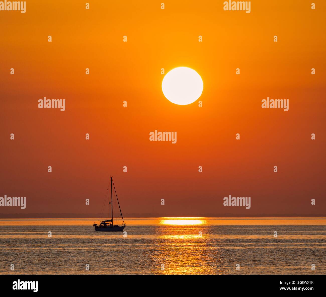 Un piccolo yacht lascia Swanage marina e si dirige verso la Manica con il sole che sorge ad est Foto Stock