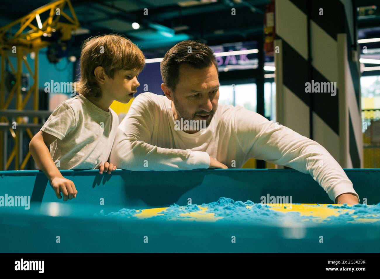 Papà e figlio sono appassionati di giocare con la sabbia cinetica nel centro di sviluppo. Sviluppo di capacità motorie. Alleviare stress e tensione Foto Stock