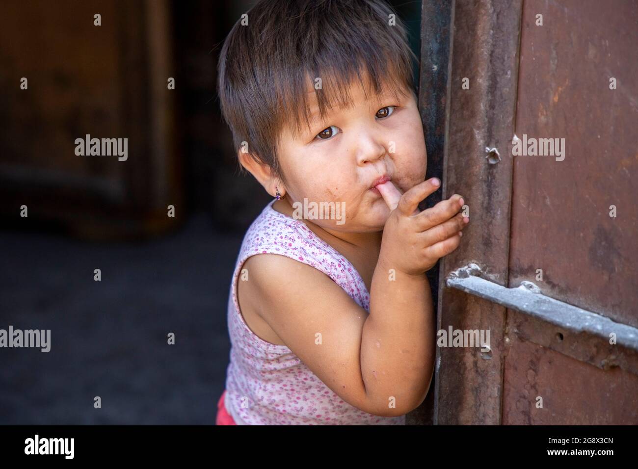 Kyrgyz ragazza succhiando il pollice e posando, Bishkek, Kirghizistan Foto Stock