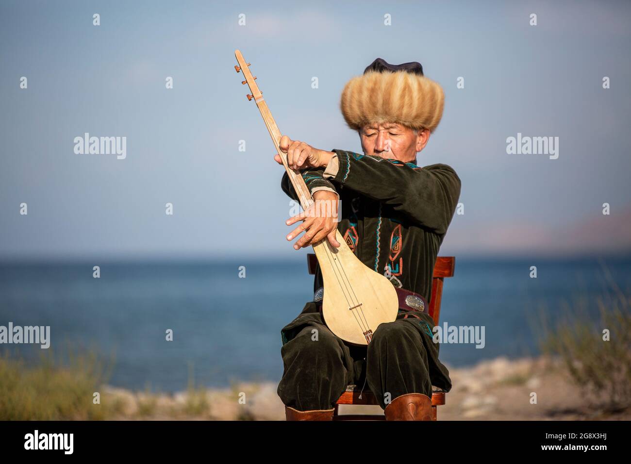 Musicista kirghiso che suona uno strumento musicale tradizionale conosciuto come Komuz a Issyk Kul, Kirghizistan Foto Stock