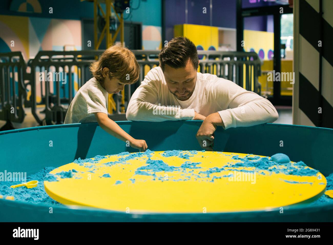 Ragazzo e suo padre stanno giocando con entusiasmo con la sabbia cinetica colorata nel centro di gioco. Terapia di sabbia. Creatività e relax. Amore parentale e. Foto Stock