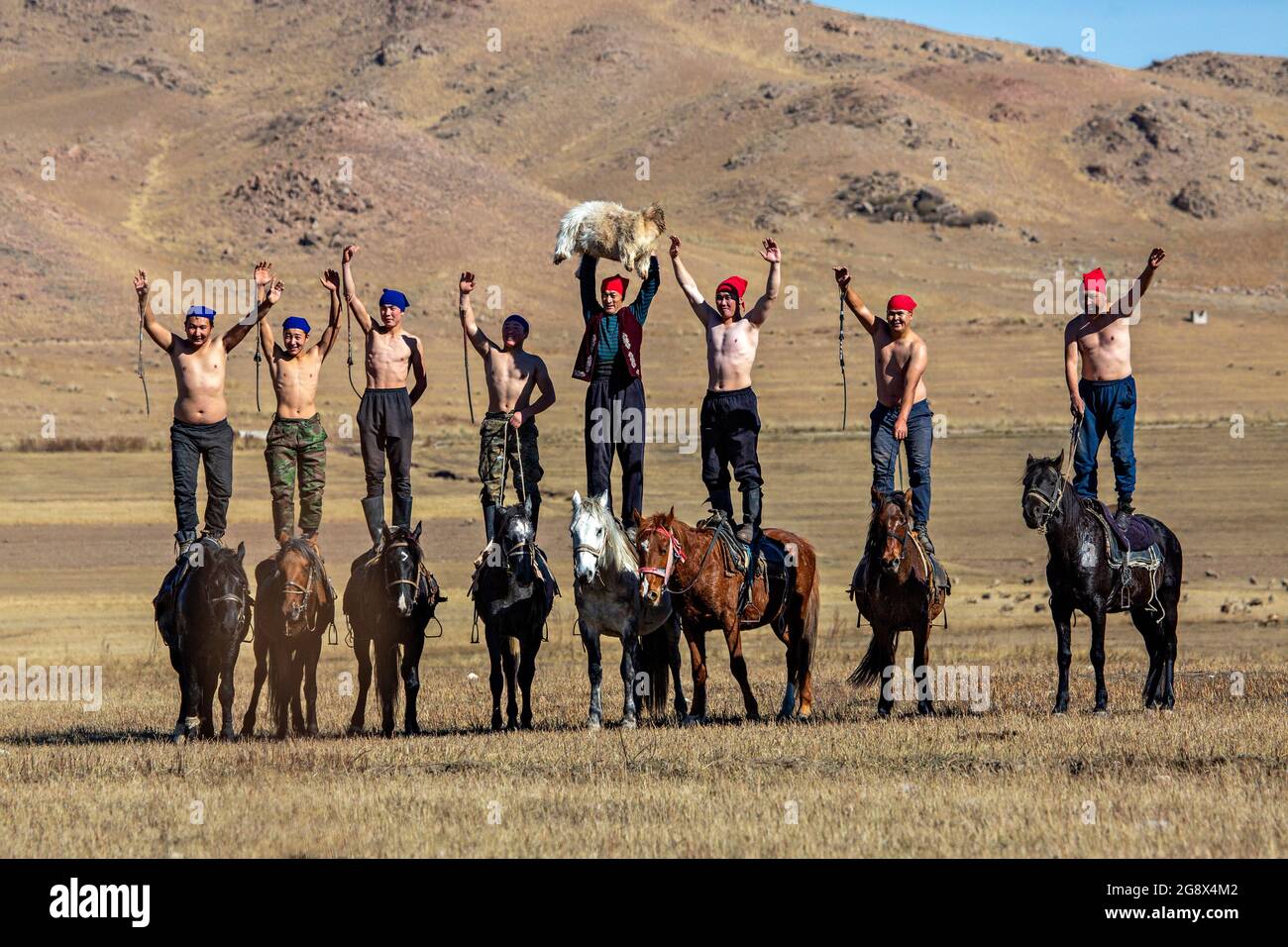 Gruppo di cavalieri del gioco nomade noto come Buzkashi o Kokpar salutare le persone alla fine della partita a Issyk Kul, Kirghizistan Foto Stock