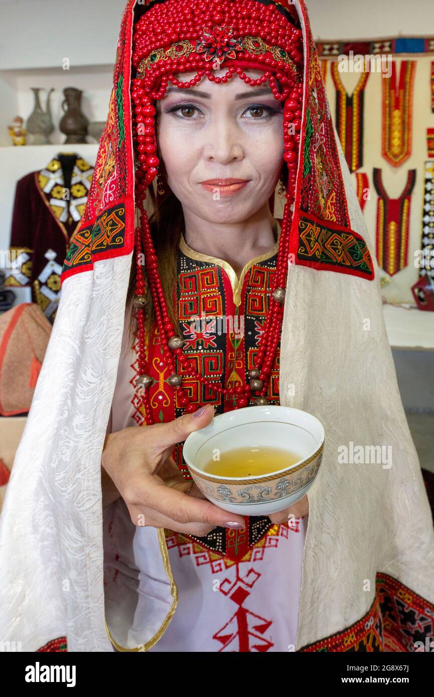 Donna uzbeka in abito da sposa tradizionale che offre tè a Nukus, Uzbekistan Foto Stock