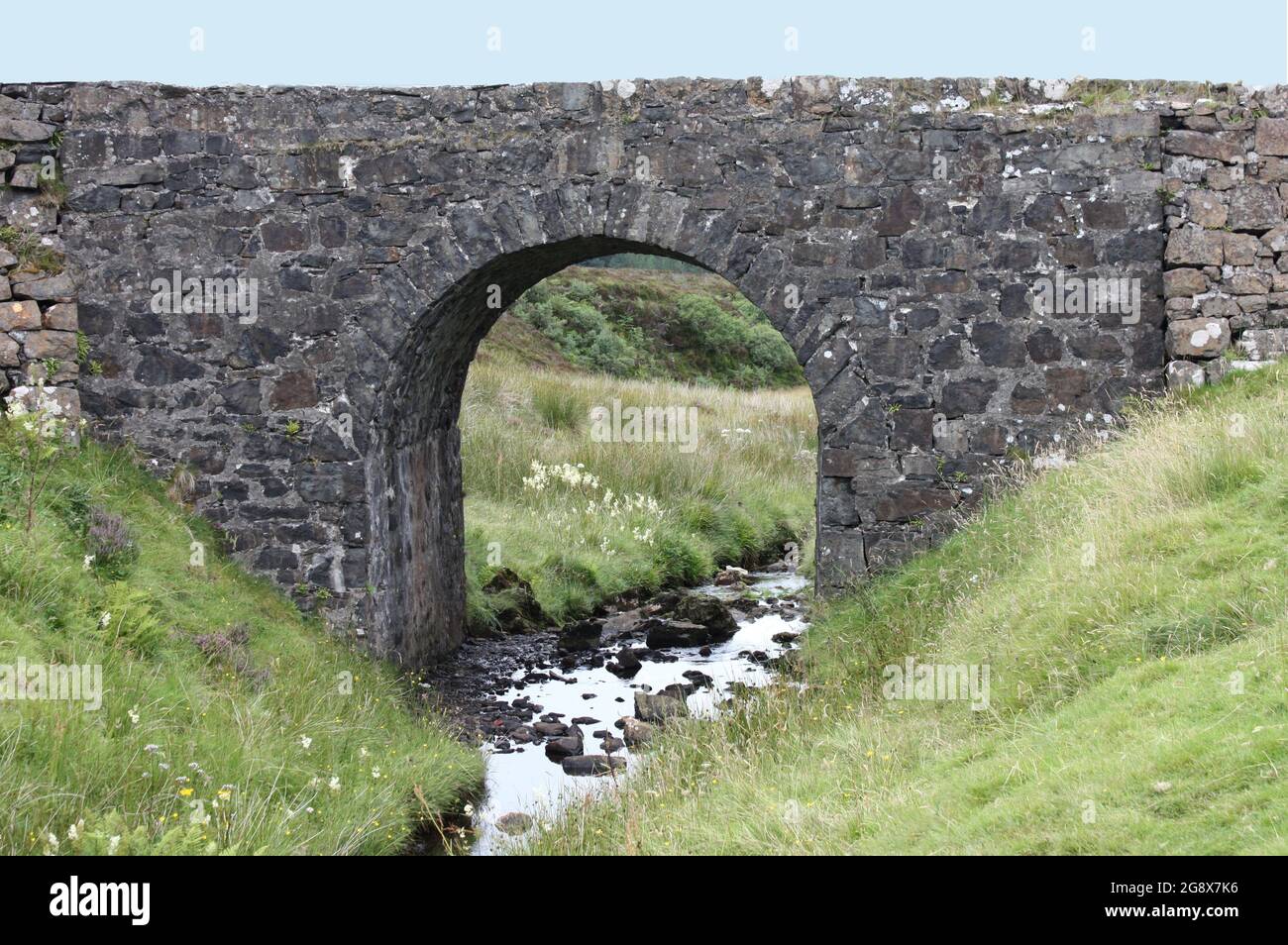 Un vecchio ponte costruito in pietra su un piccolo ruscello. Foto Stock