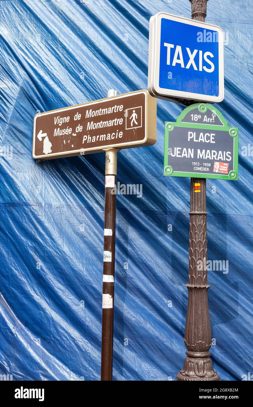 Vari cartelli di fronte a un telone blu su Place Jean Marais a Montmartre, Parigi Foto Stock