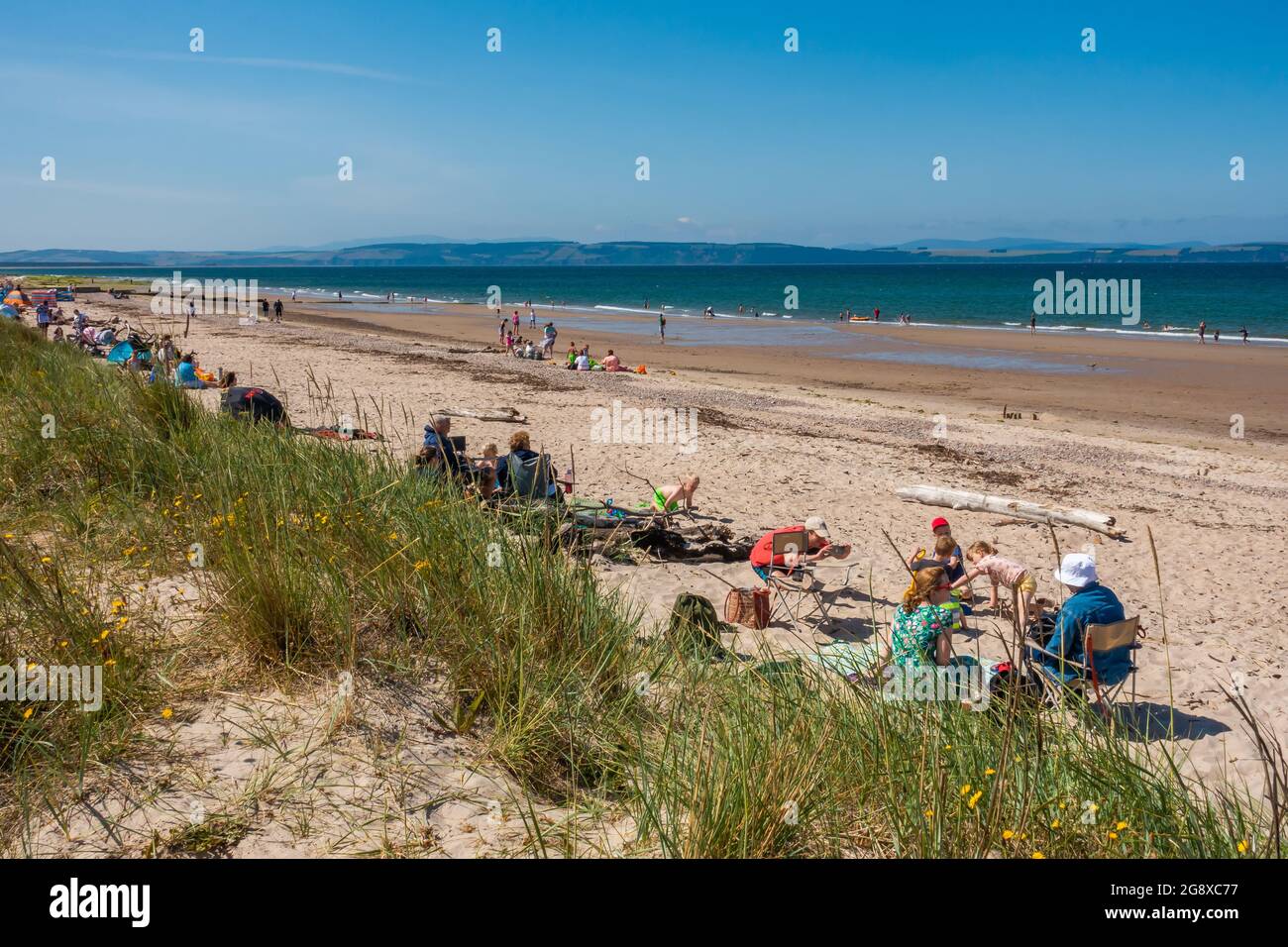 Bagnanti e nuotatori sulla spiaggia di Nairn, Scozia, in una giornata estiva soleggiata. Foto Stock