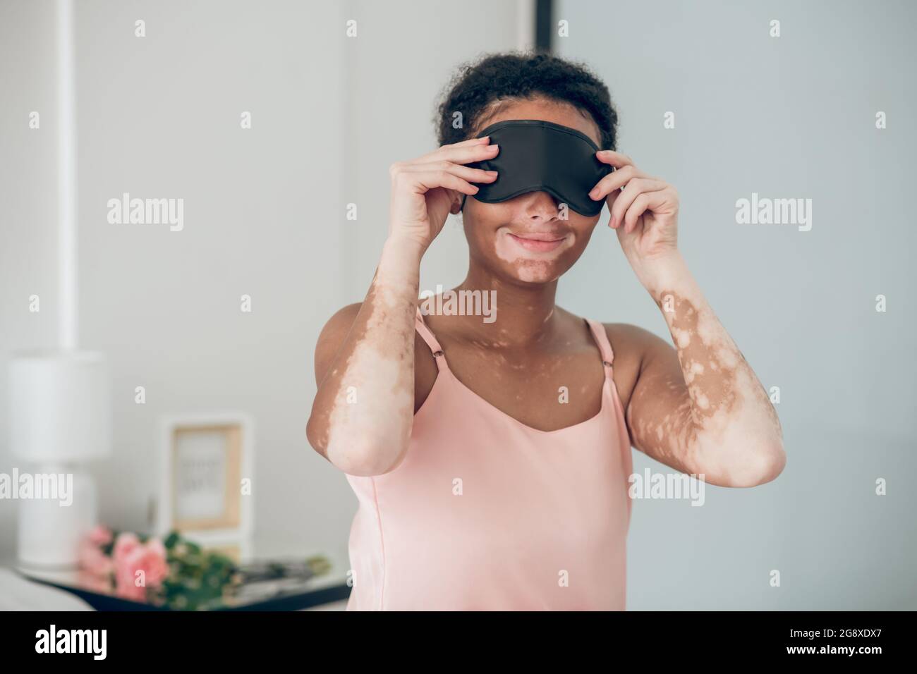 Giovane mulatta che mette su una maschera per dormire Foto Stock