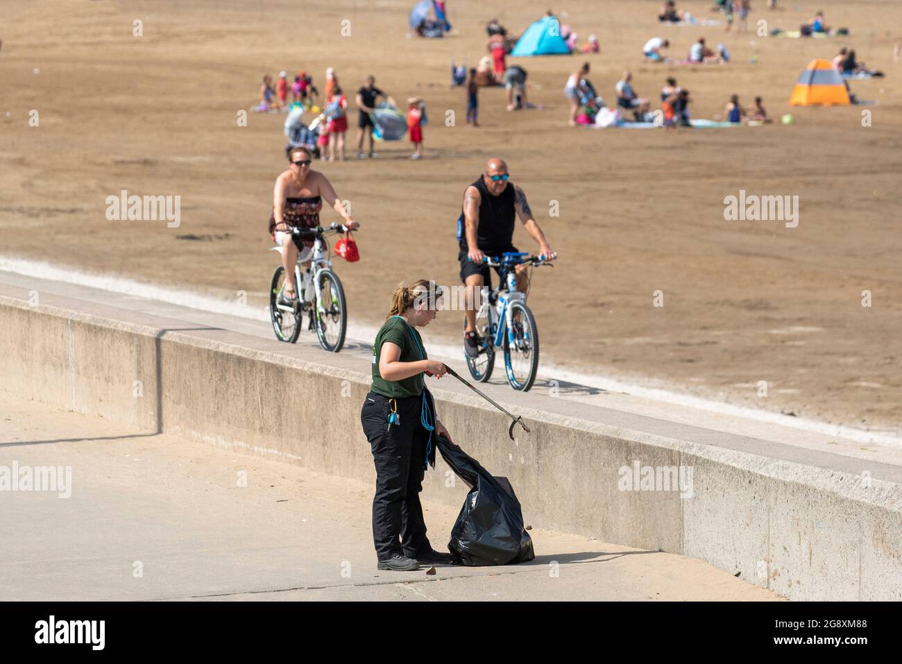 Donna rifiuta di raccogliere Southport, Merseyside. Regno Unito Meteo;Luglio 2021. Inizia la giornata con il sole mentre l'onda di calore continua. I residenti locali e i vacanzieri si esercitano in modo leggero sul lungomare e sulle sabbie del resort di fronte alla spiaggia. Credit: MediaWorldImages/AlamyLiveNews Foto Stock