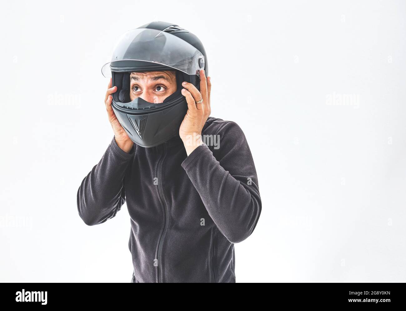 Uomo con un casco da moto che dà un gesto di pollice su. Isolato sulla  parete bianca dello studio Foto stock - Alamy