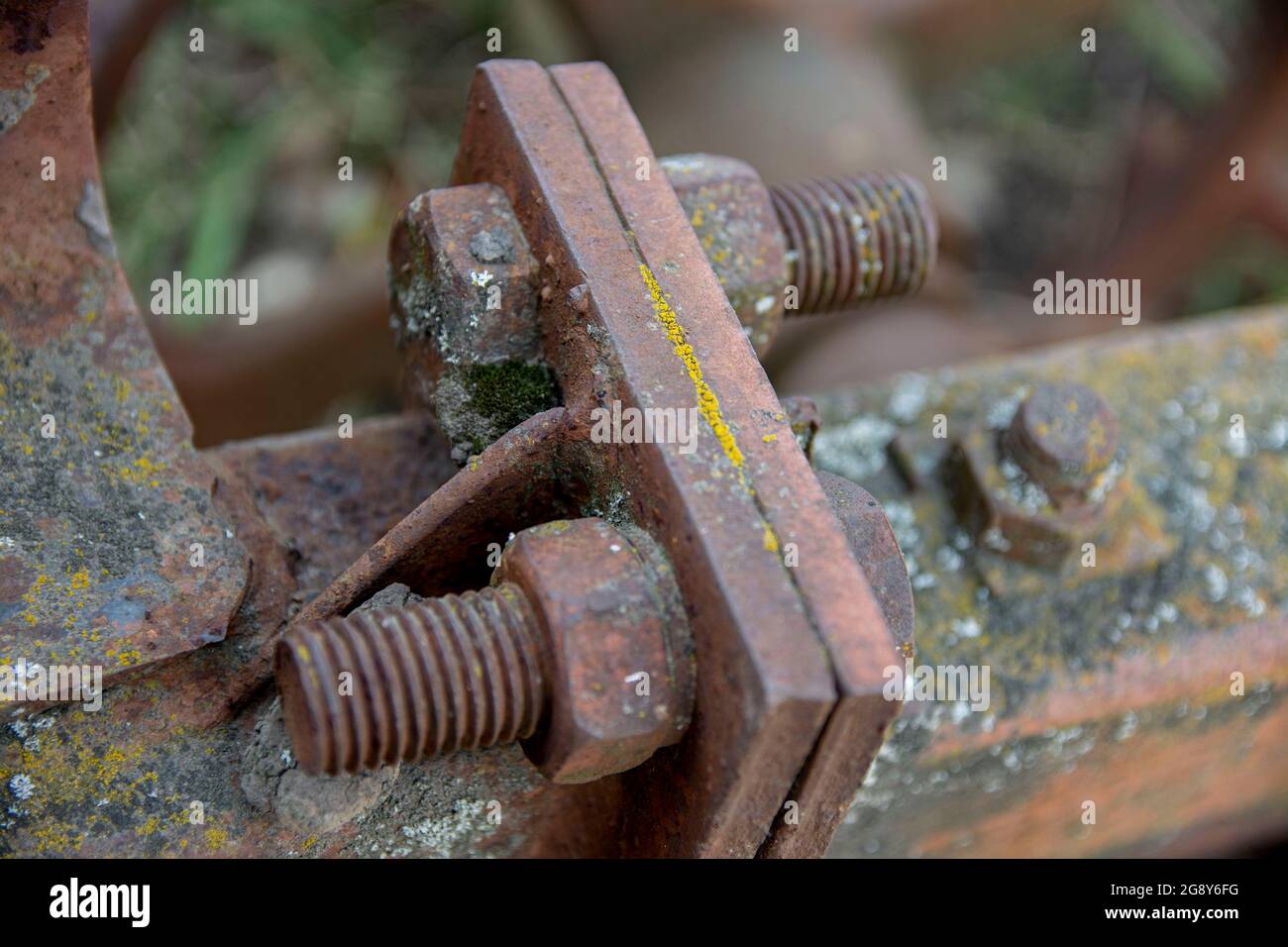Dettagli arrugginiti di vecchie auto abbandonate. Ingranaggi, catene, pulegge si arrugginiscono nell'apertura. Parti metalliche ricoperte di muschio di macchine agricole. Foto Stock