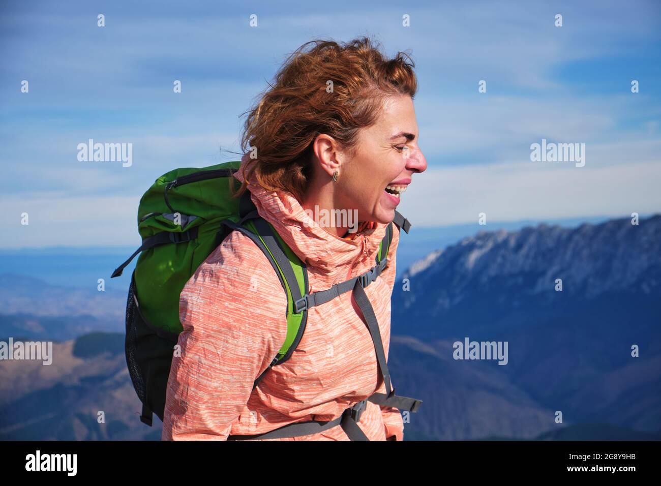 Ritratto di una donna che ride in montagna, con i suoi capelli che soffiano nel vento. Ragazza escursionista nei monti Carpazi. Foto Stock