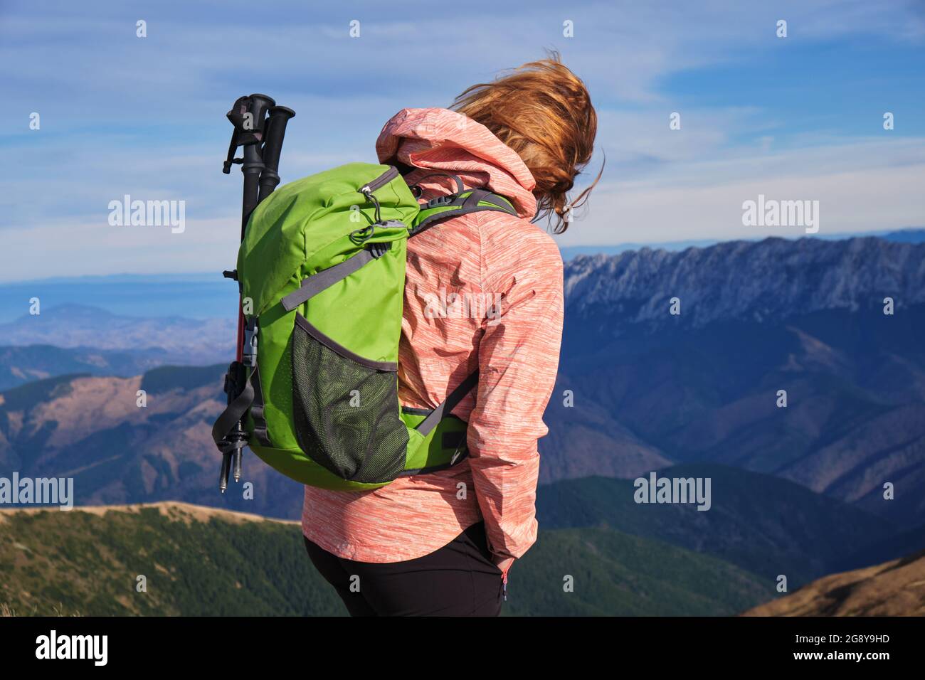 Ragazza escursionista con zaino verde e bastoni da trekking nelle montagne dei Carpazi. Foto Stock