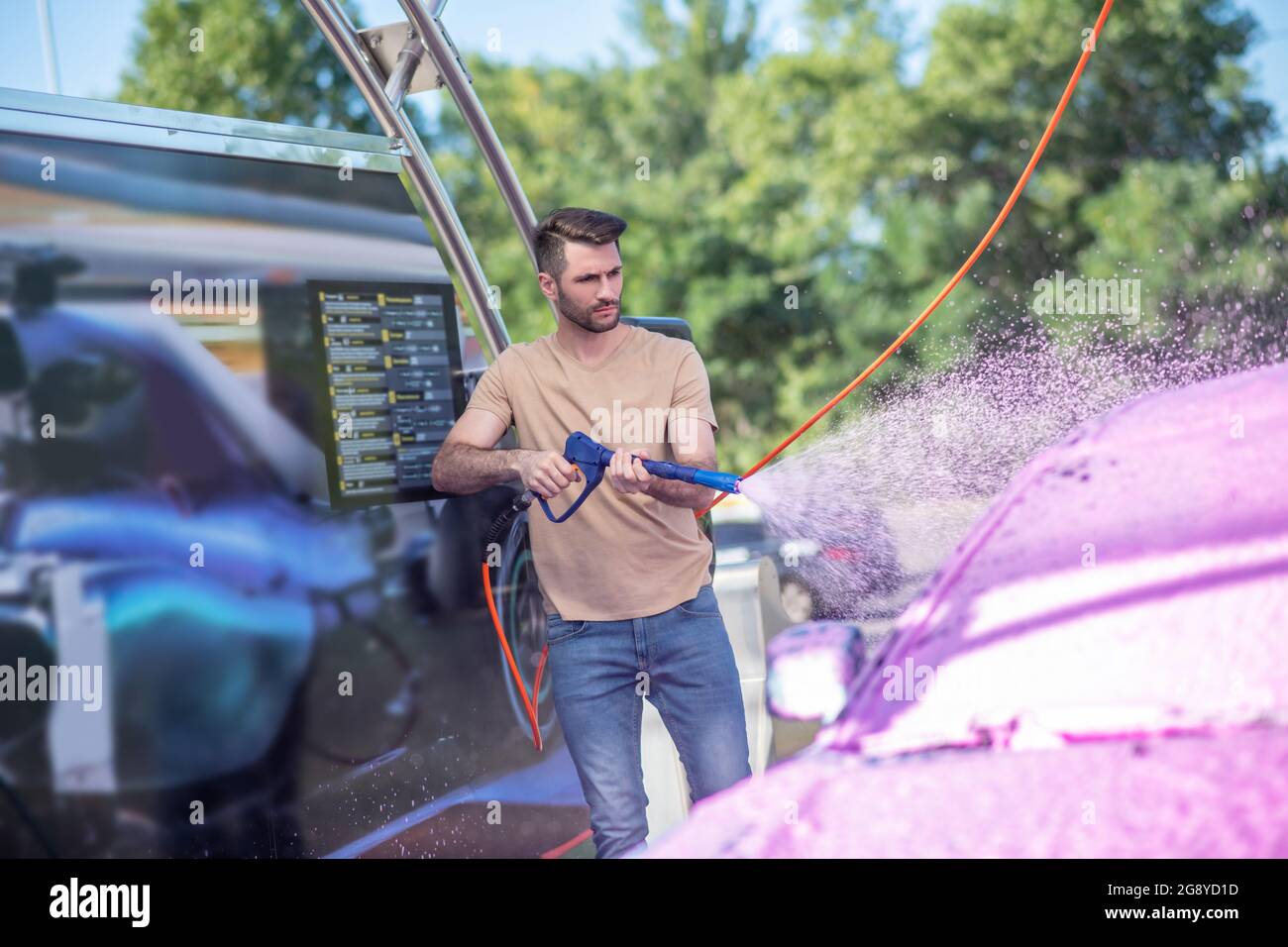 Servizio auto operaio lavando auto all'aperto Foto Stock