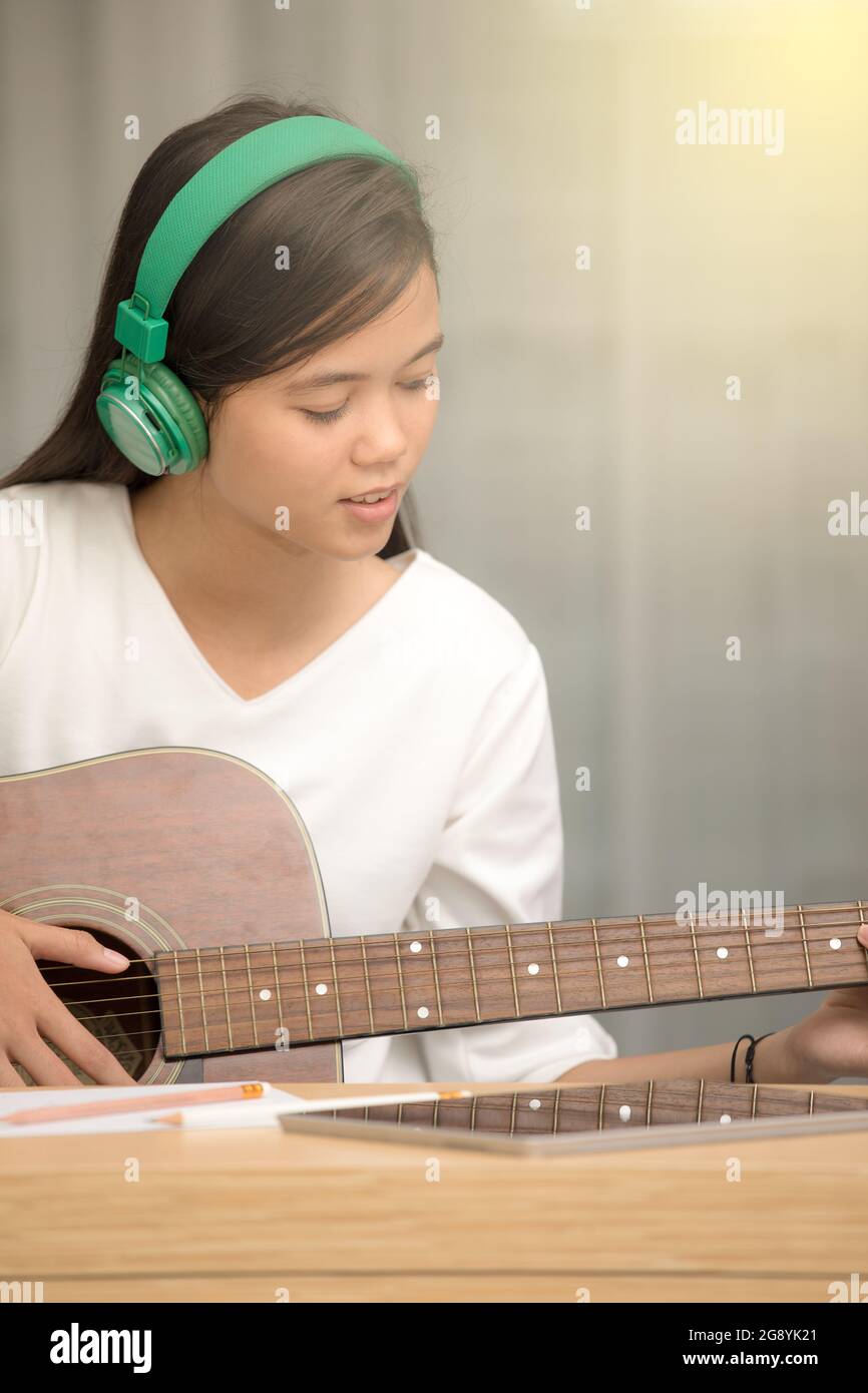 Giovane ragazza asiatica che suona la chitarra e cerca di essere compositore di musica, scrittore di canzone Foto Stock