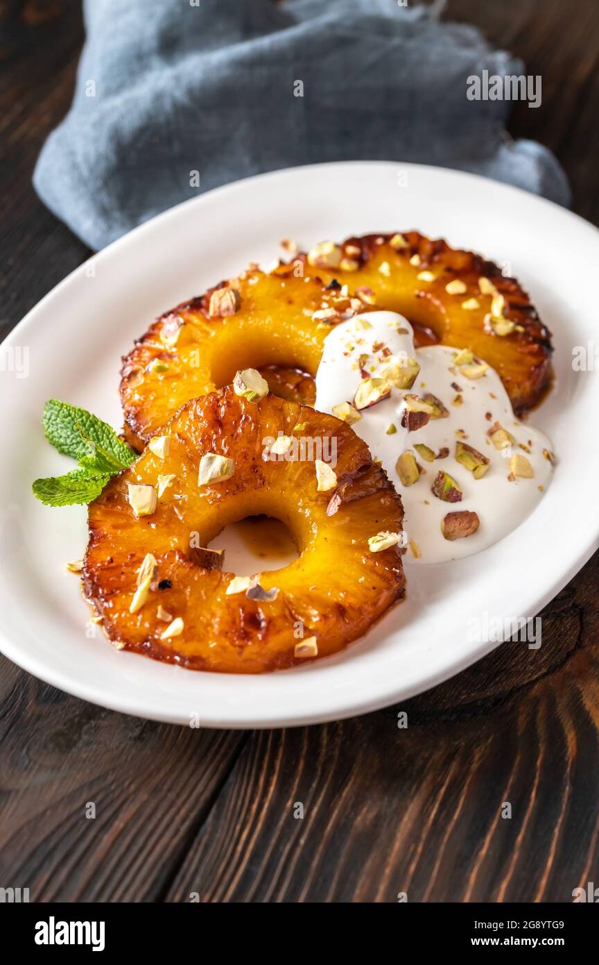 Ananas caramellato con panna montata e pistacchi sul piatto piastra Foto Stock