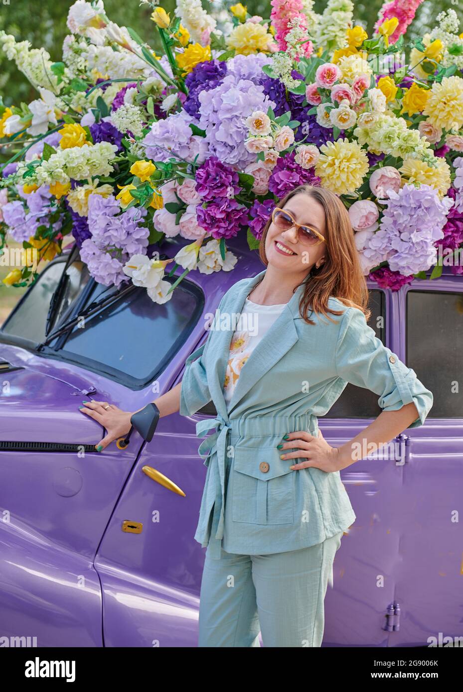 donna con occhiali e un'auto colorata di diversi colori Foto Stock
