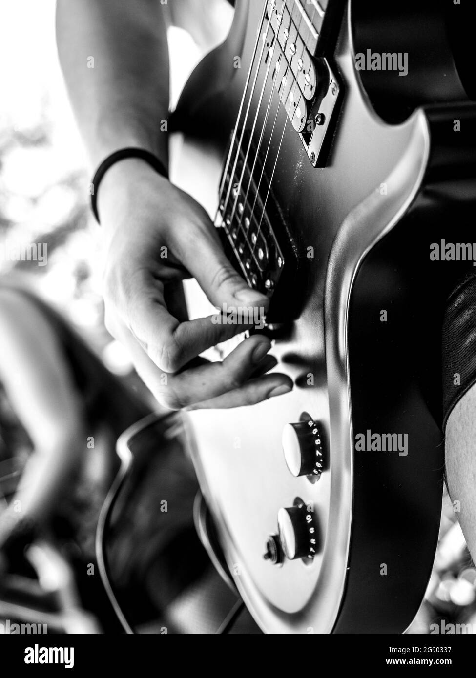 Immagine verticale di un musicista che suona una chitarra elettrica su uno sfondo sfocato Foto Stock