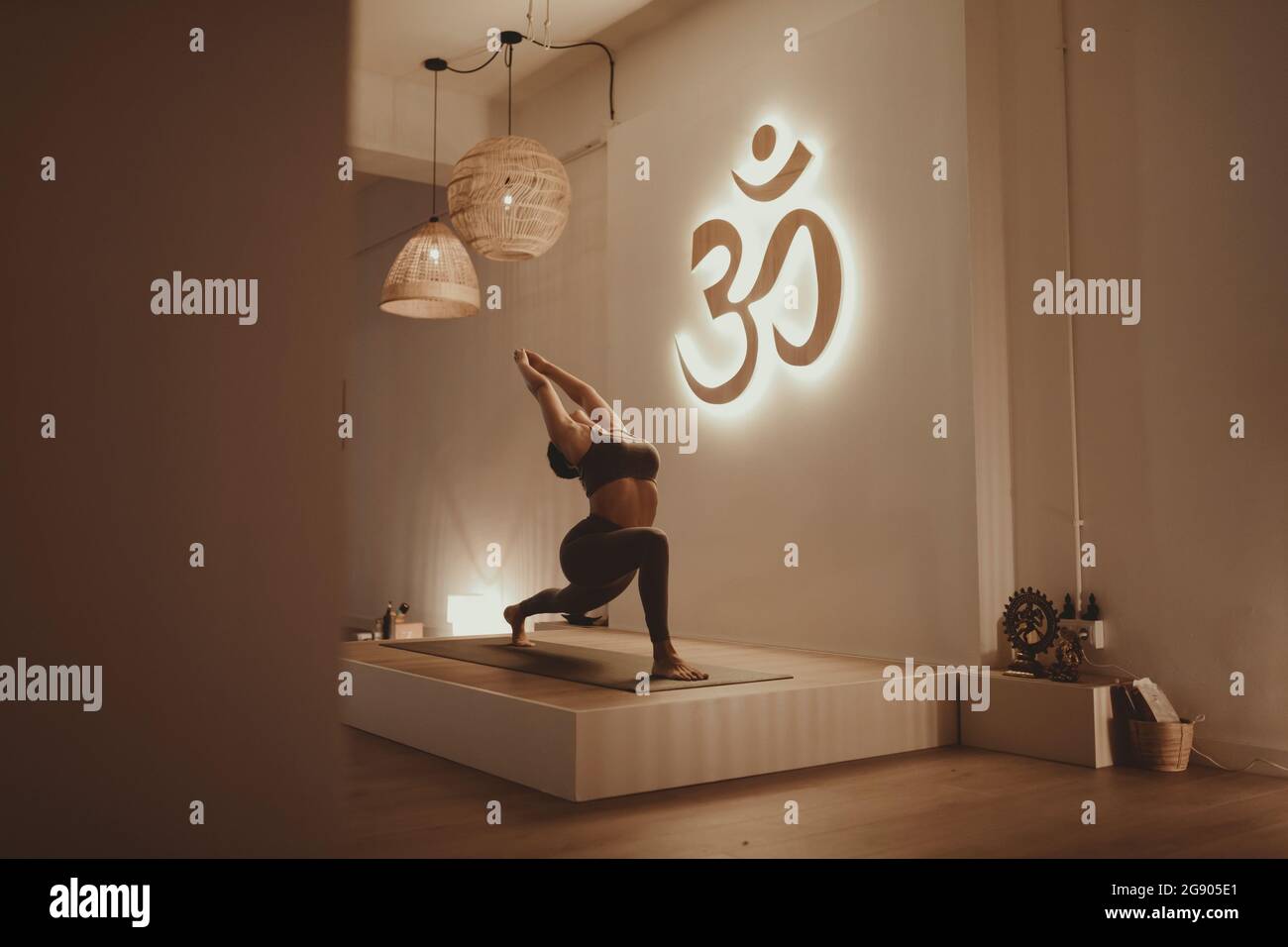 Istruttore di yoga femminile con le braccia alzate piegandosi mentre si pratica da Om Symbol Foto Stock
