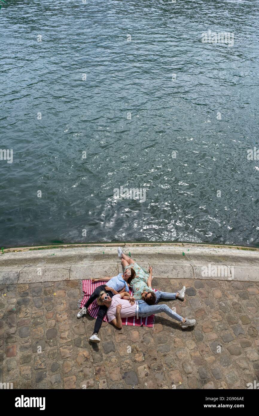 Amici maschi e femmine che giacciono sul lungomare lungo il fiume Foto Stock