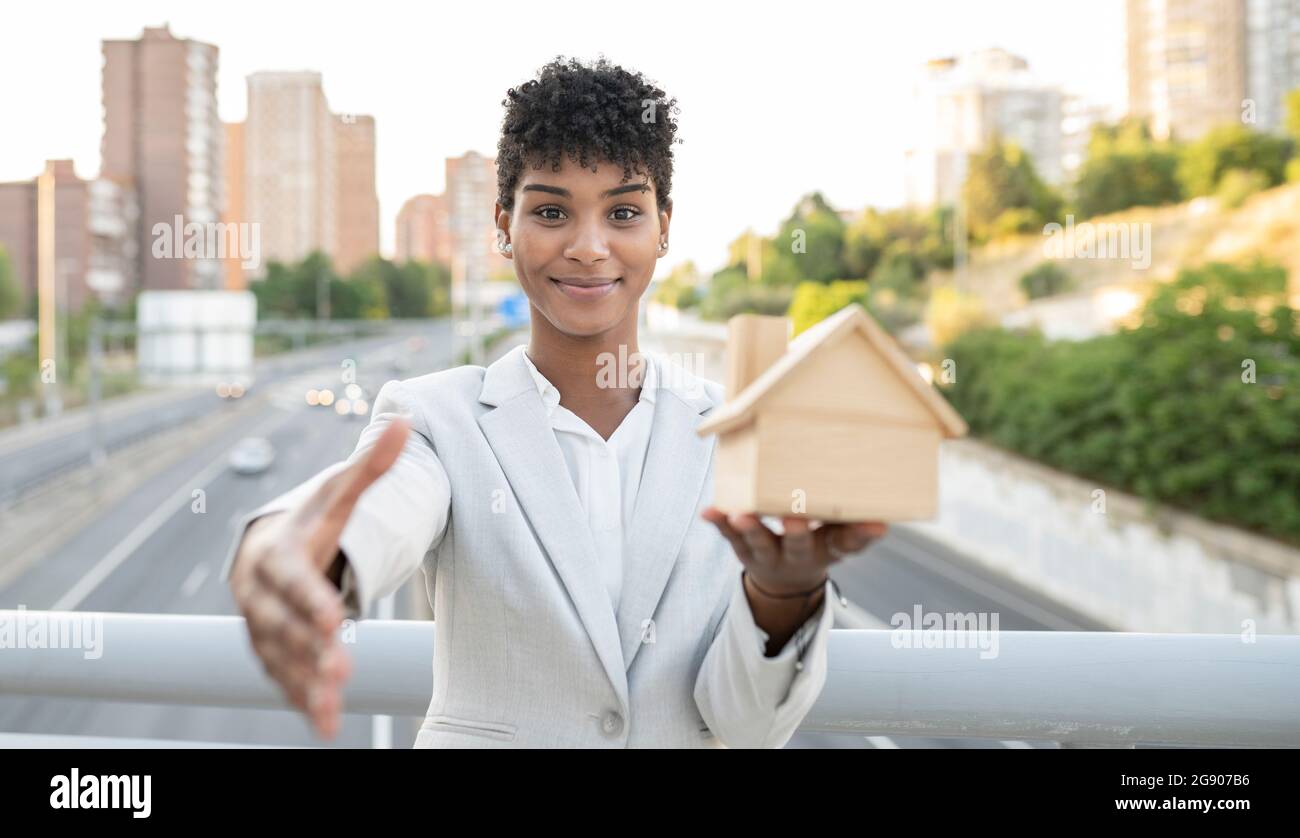 Donna di vendita che tiene il modello di casa mentre saluto con handshake sul ponte Foto Stock