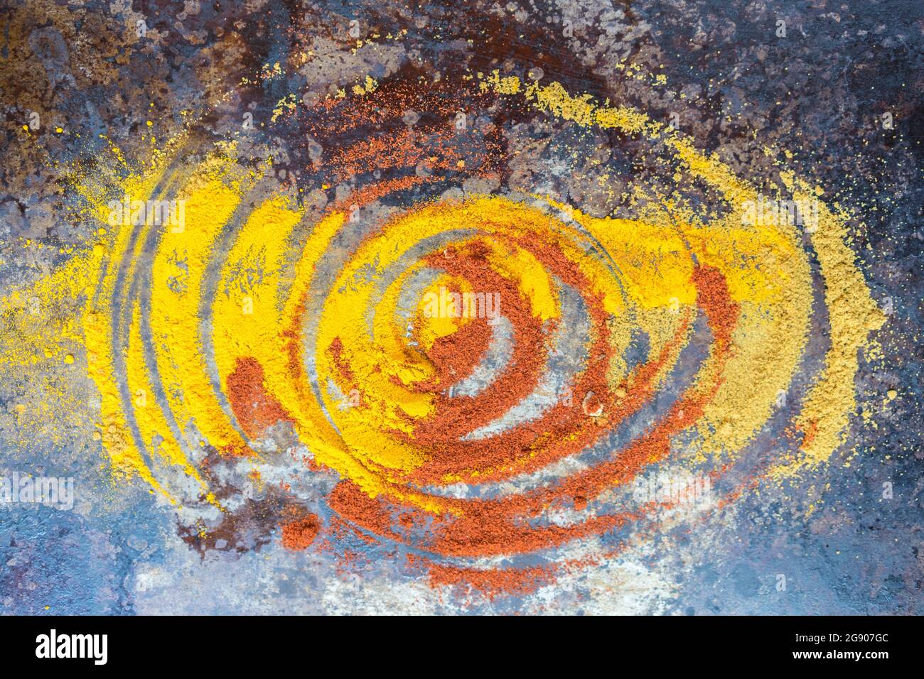 Studio di spezie gialle e arancioni mescolando insieme in un motivo di turbolenza Foto Stock