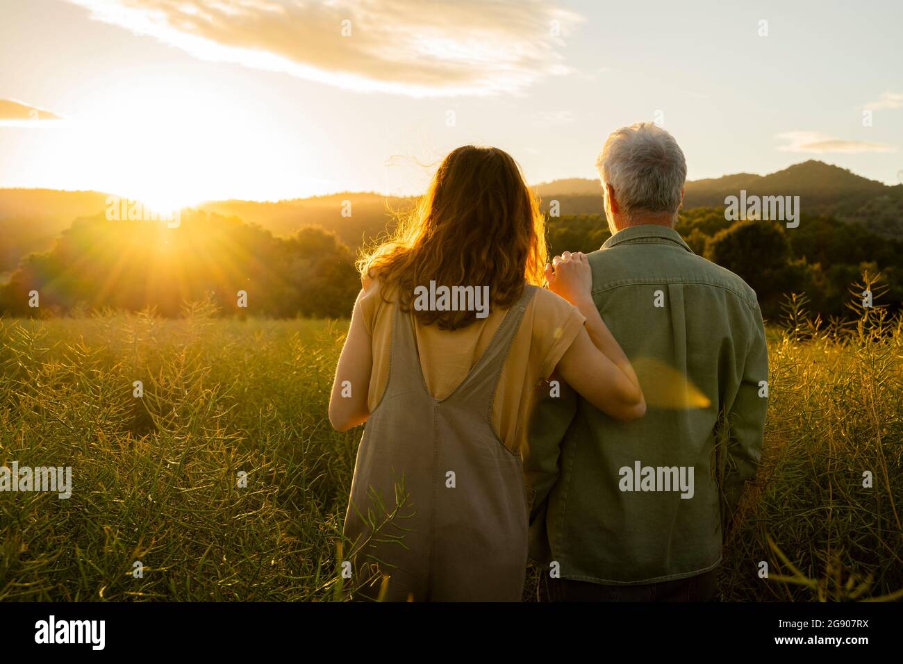 Figlia e padre che guardano la vista del tramonto mentre sono in piedi in campo Foto Stock