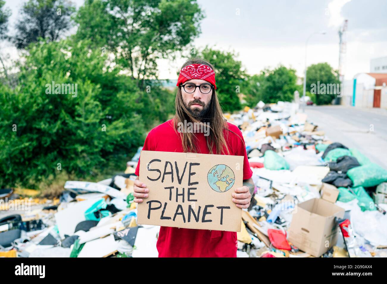 Uomo serio che tiene salvare il cartone del pianeta su spazzatura dump Foto Stock