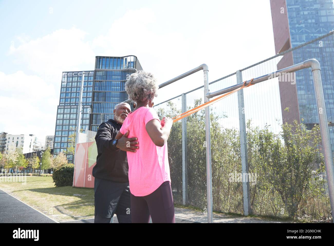 Uomo che aiuta la donna ad esercitarsi con la fascia di resistenza al parco Foto Stock